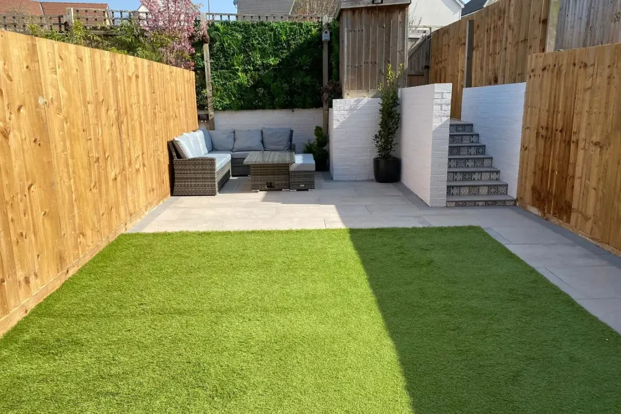 Finished landscaped garden with porcelain patio, artificial lawn, white brick walls and tiled steps