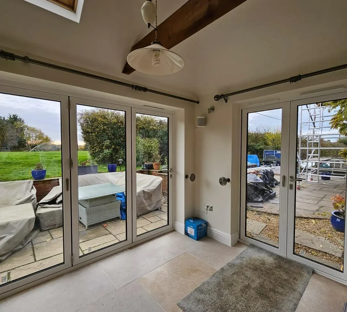 Garden room interior with limestone floor, exposed oak beam and bifold doors on two sides