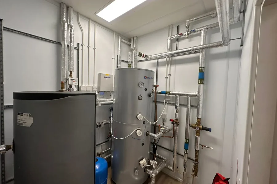 Neatly installed plant room with hot water cylinders, buffer tank and labelled insulated pipework