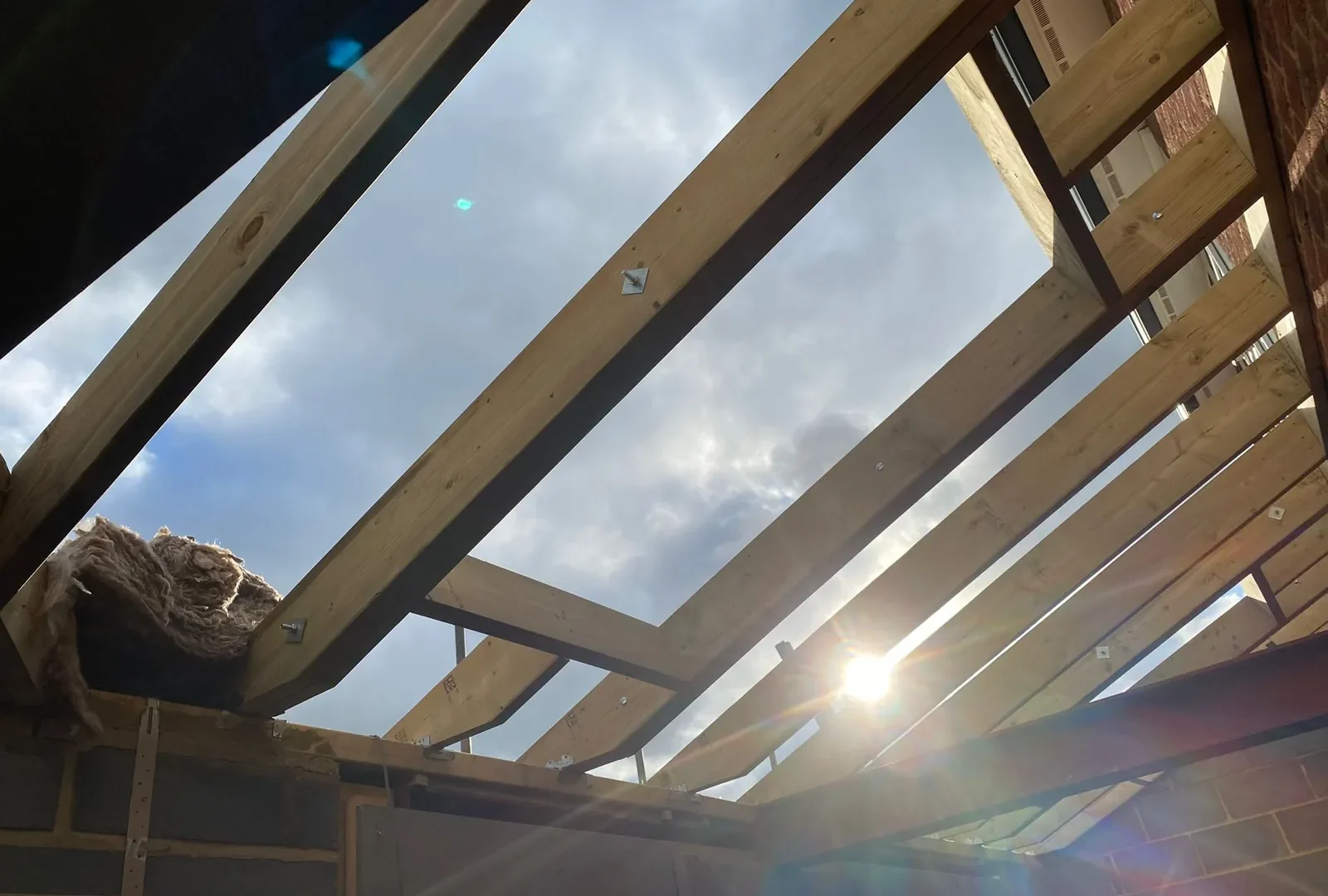 New roof structure under construction showing steel beams and timber joists against the sky