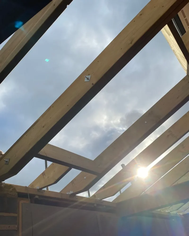 New roof structure under construction showing steel beams and timber joists against the sky