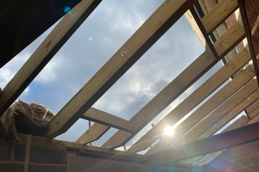 New roof structure under construction showing steel beams and timber joists against the sky
