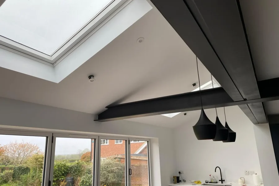 Finished kitchen extension with vaulted ceiling, dark exposed steel beams, skylights and bifold doors to the garden