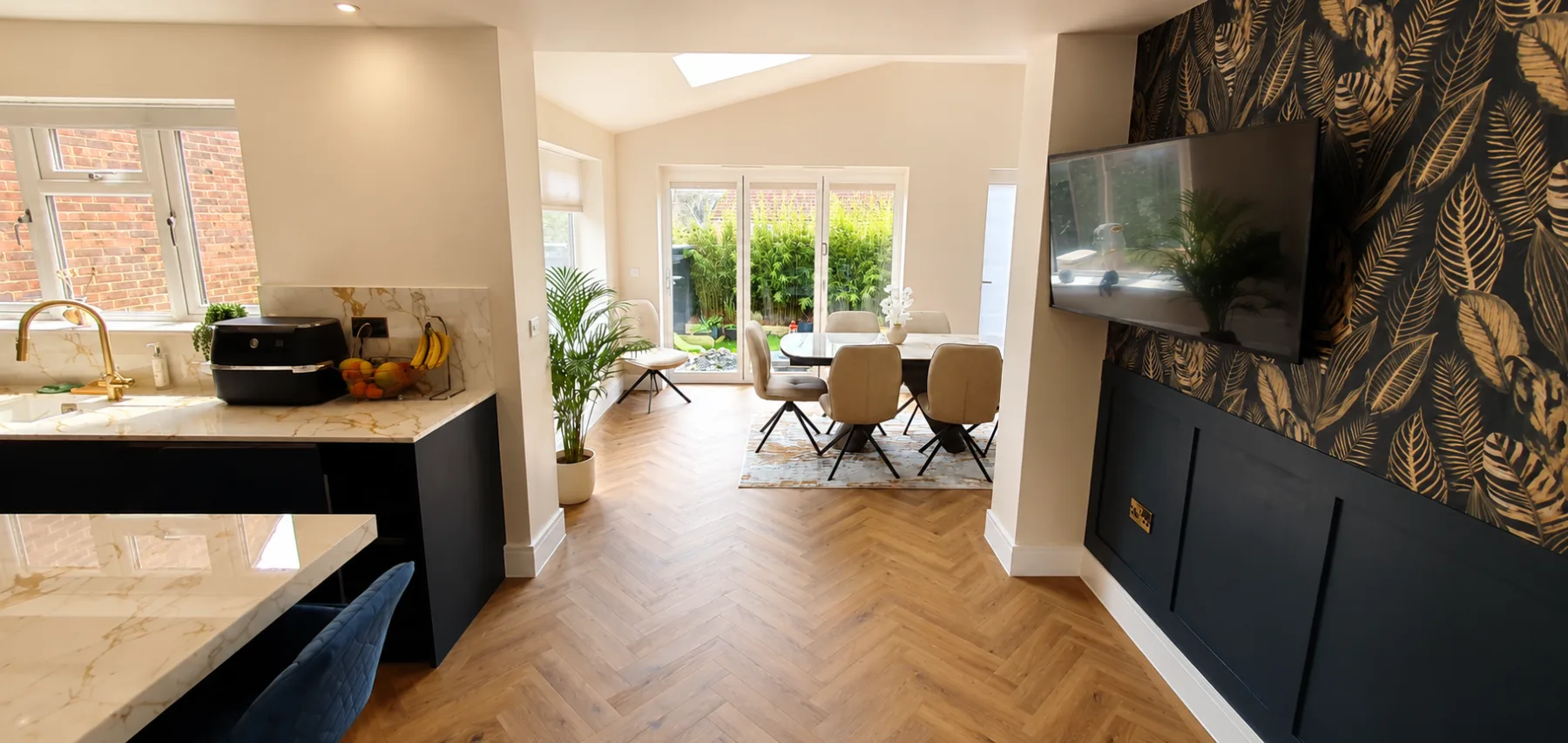 Kitchen diner extension with french doors to the garden, botanical feature wall and herringbone flooring