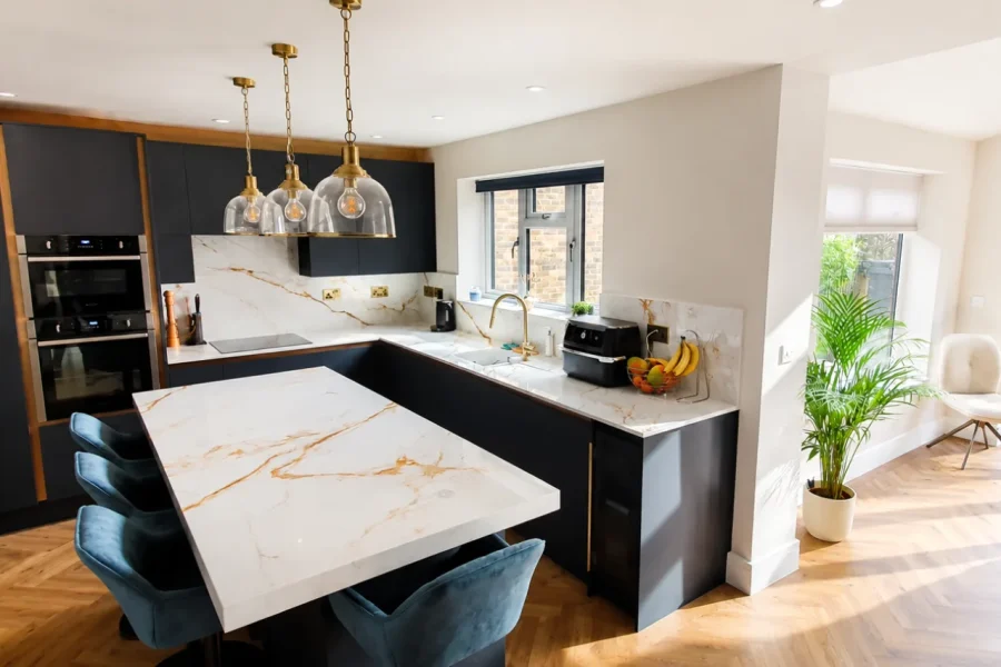 Open-plan kitchen extension with a marble effect island, brass pendant lights and herringbone flooring