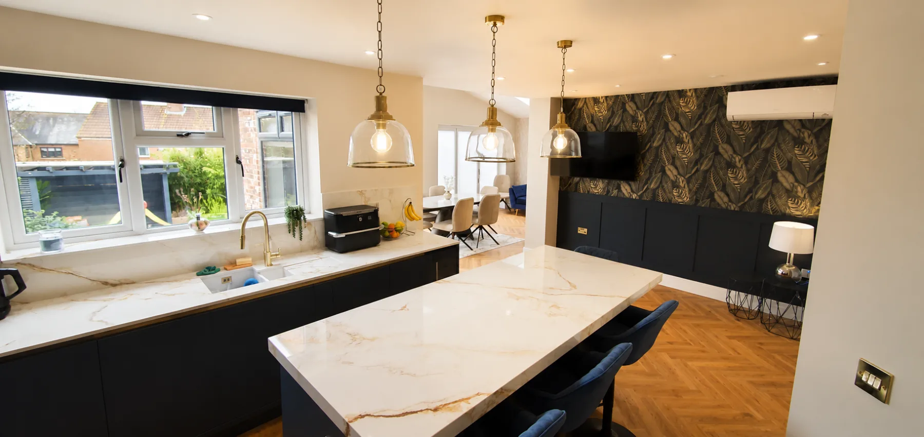 Kitchen extension with a window run over the sink and an open-plan dining area beyond