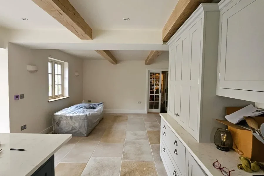 Renovated kitchen with exposed oak ceiling beams, pale shaker cabinetry, quartz worktops and limestone flagstone flooring