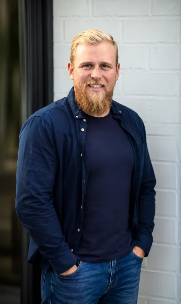 Steven from the DWG Construction team, in a navy shirt against a white brick wall