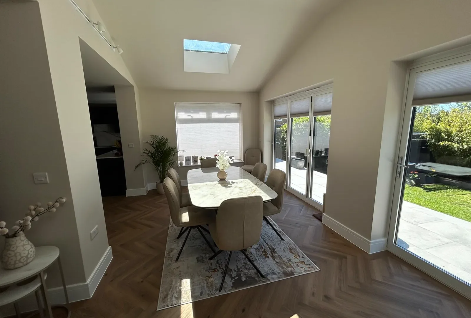 Bright open-plan dining extension with a rooflight, herringbone flooring and sliding doors to the patio